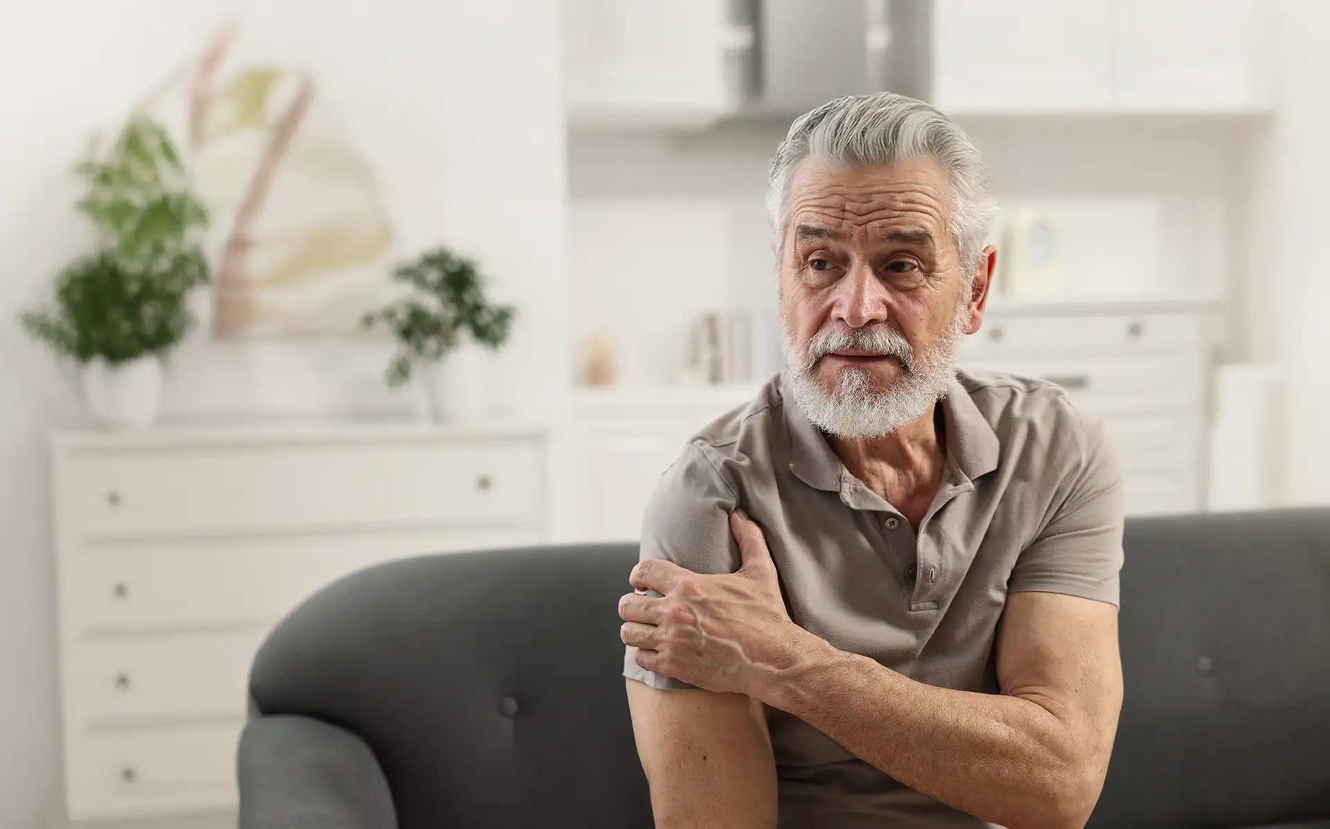 Man holding his shoulder in discomfort from arthritis