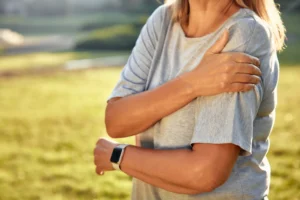 women wrapping her hand around her injured shoulder due to shoulder joint pain.
