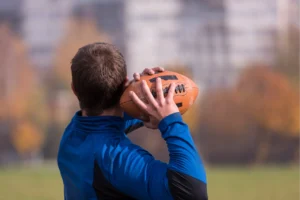 A man throwing a football overhead, a repetitive motion linked to rotator cuff tears in athletes