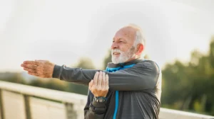 Older man stretching his arm and shoulder outdoors during rotator cuff surgery recovery