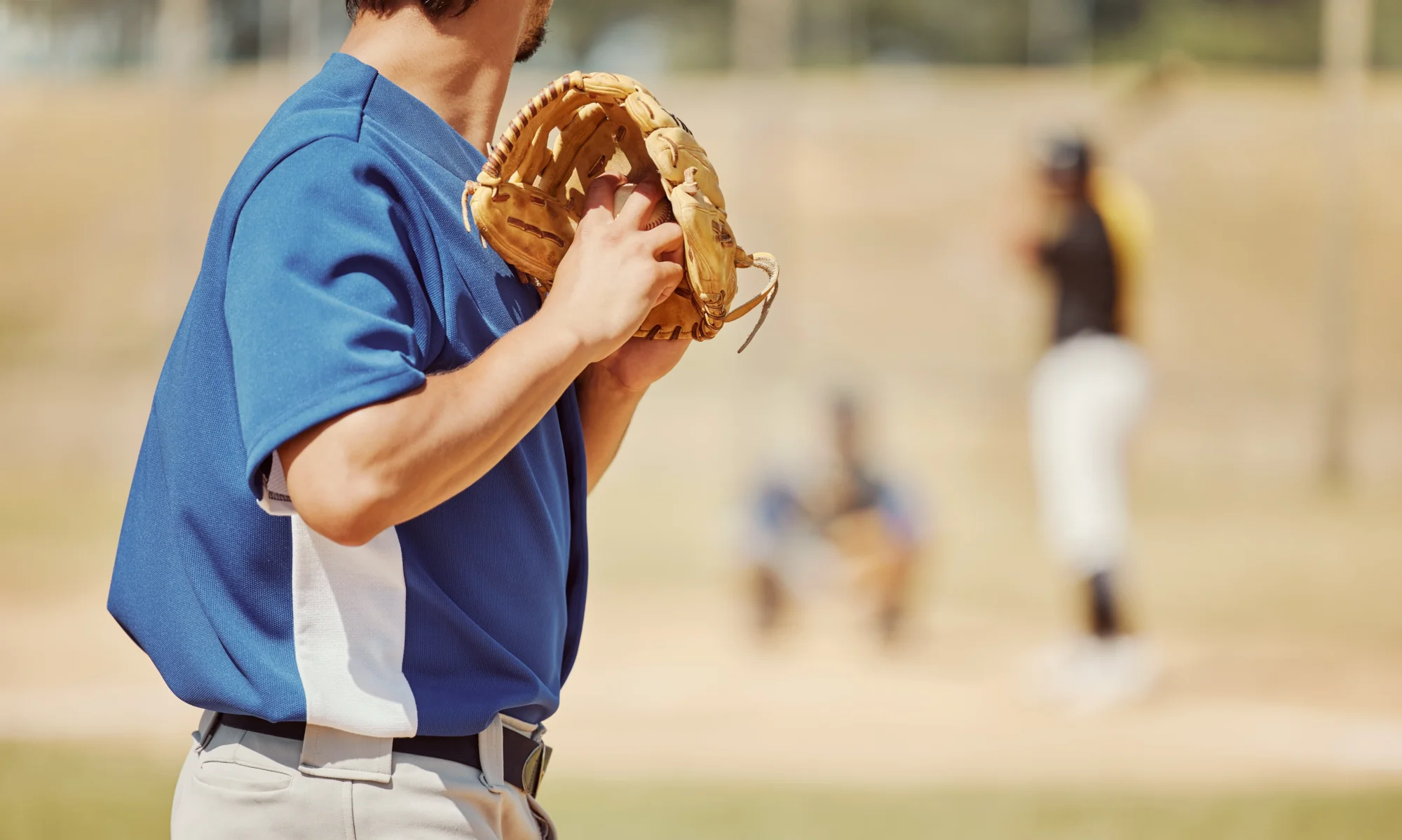 Close-up of a baseball pitcher holding a ball in his glove near his shoulder.